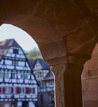Fachwerkgebäude im Klosterhof Maulbronn durch einen steinernen Fensterbogen betrachtet | © Kraichgau-Stromberg Tourismus e.V. | Christian Ernst