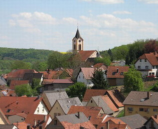 Blick auf eine Kirche auf einer Anhöhe und Häuserdächer | © Stadt Sinsheim
