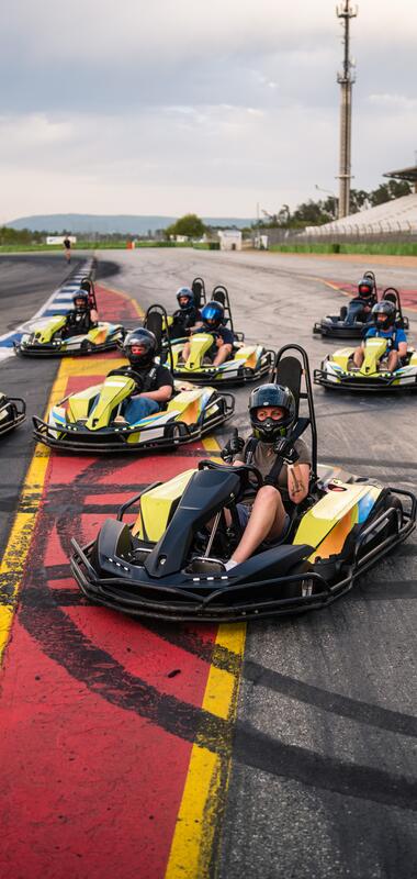 Mehrere Personen sitzen in gelb-schwarzen Karts auf einer Rennstrecke mit Tribünen im Hintergrund | © Hockenheim-Ring GmbH