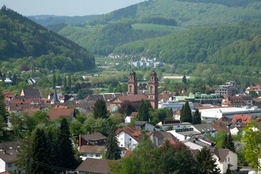 Blick auf die katholische Kirche in Eberbach mit zwei Türmen, umgeben von Wohnhäusern und bewaldeten Hügeln im Hintergrund | © Landratsamt Rhein-Neckar-Kreis; Foto Dorothea Burkhardt