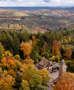 Luftaufnahme einer herbstlichen Waldlandschaft im Odenwald mit einem großen Gebäude und einem Turm in der Mitte | © Landratsamt Rhein-Neckar-Kreis; Foto Sebastian Weindel